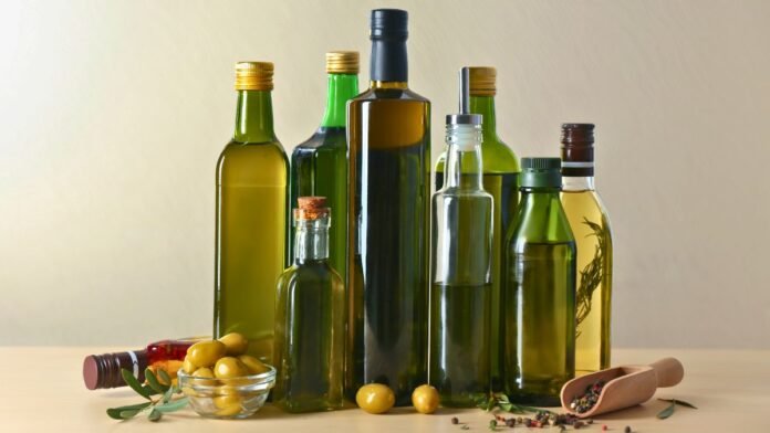 Distintas botellas de aceite de oliva junto a aceitunas